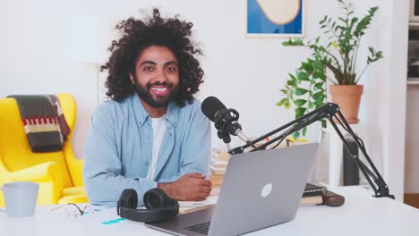 young arabian man takes off headphones and looks at camera sits at office table