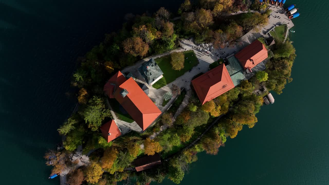 Zoom out aereo dall'alto del Castello di Bled con tetti rossi su una scogliera sopra il Lago di Bled in Slovenia.