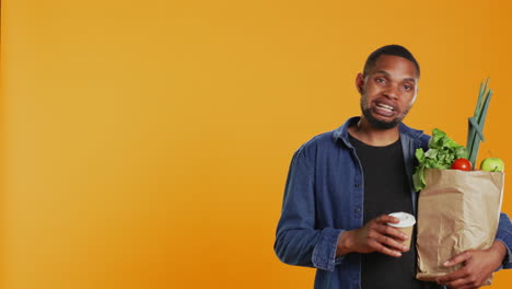 Relaxed-carefree-person-drinking-a-coffee-cup-and-carrying-his-groceries