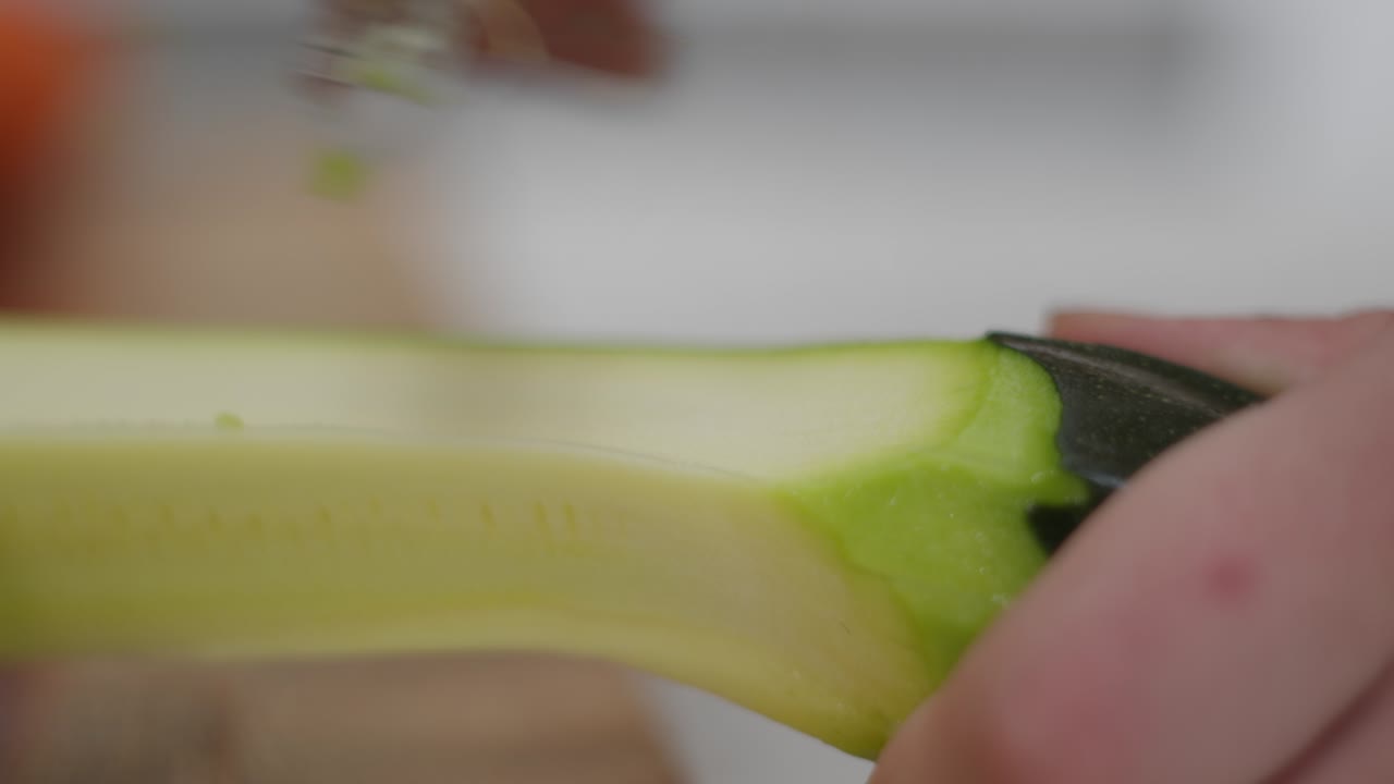 persona pelando un pepino con la mano, vista de cerca