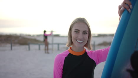 Young-Caucasian-woman-holds-a-surfboard-on-the-beach,-with-copy-space