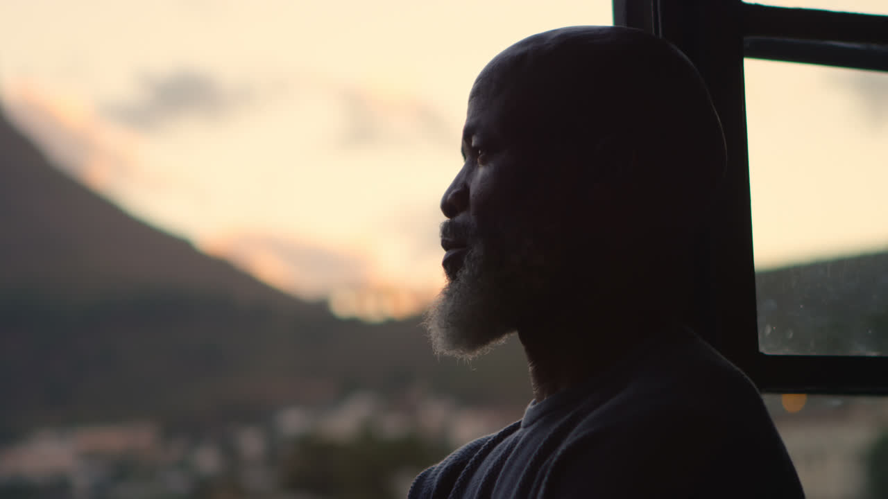 hombre mayor mirando por la ventana en casa 4k