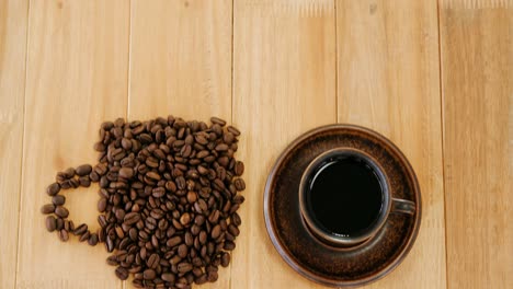 Black-coffee-with-coffee-beans-forming-shape-of-cup