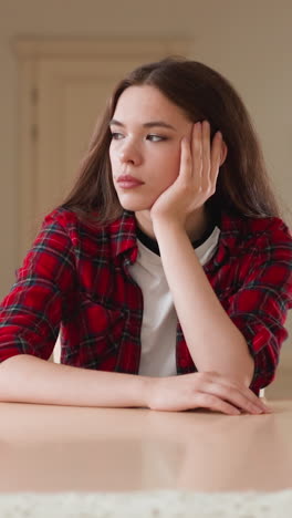 unhappy woman sits at dining table in apartment. young student thinks about lack of money for monthly rent in kitchen. difficult situation in life