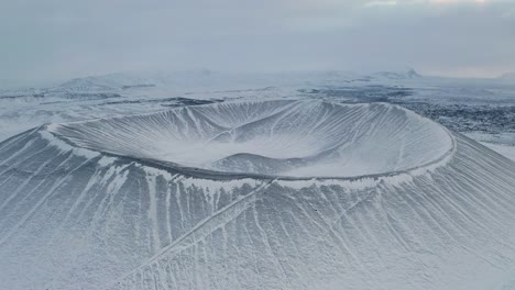 아이슬란드에서 흐린 날 동안 눈 덮인 hverfjall 분화구 화산의 공중 역방향 샷