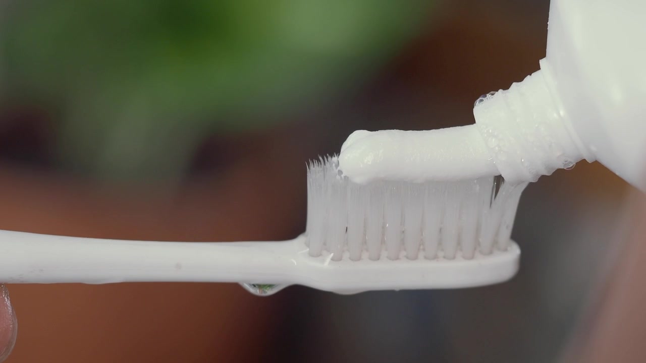 Squeezing White Toothpaste onto a Toothbrush
