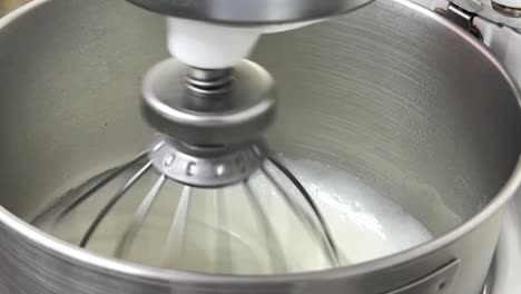 slow motion delicious icing meringue buttercream mixing in the heavy duty mixer in the commercial bakery setting, close up shot
