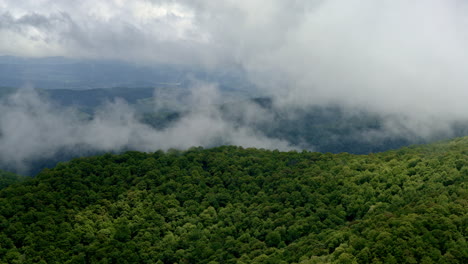 cinematic drone view as fog and clouds engulf the smoky mountain ridges