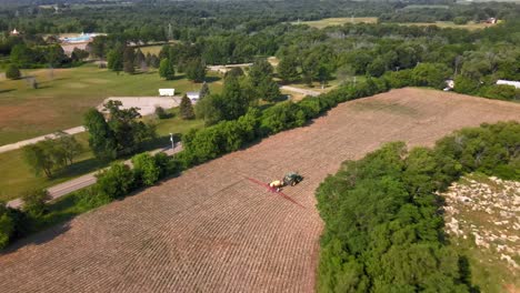 Vista-Aérea-Del-Tractor-Agrícola-Rociando-Herbicidas-Y-Pesticidas-En-El-Campo-En-Janesville,-Wisconsin