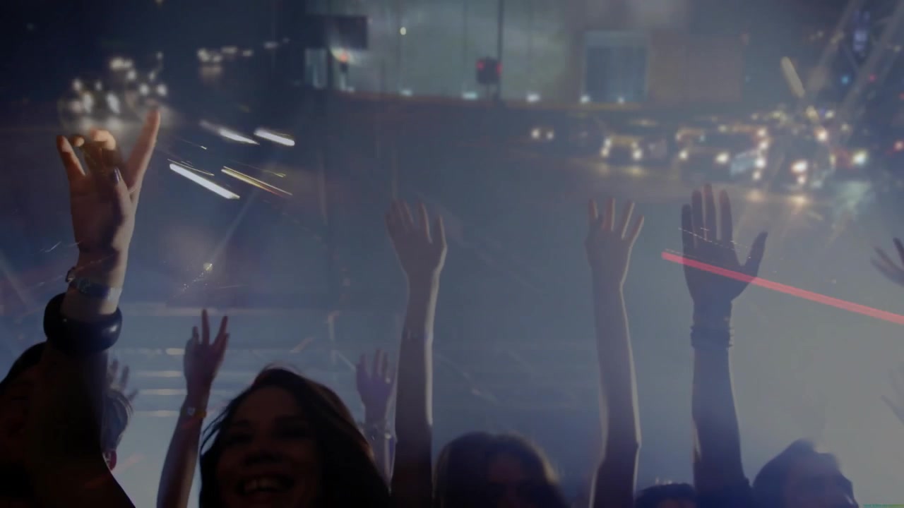 Apertura con fasci LED in movimento che fendono la foschia, folla di un concerto che alza le braccia e balla al ritmo di luci pulsanti