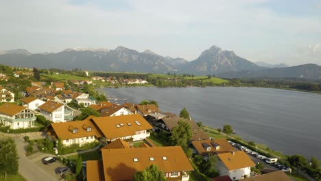 picturesque aerial view of european village on a lake with mountains in background