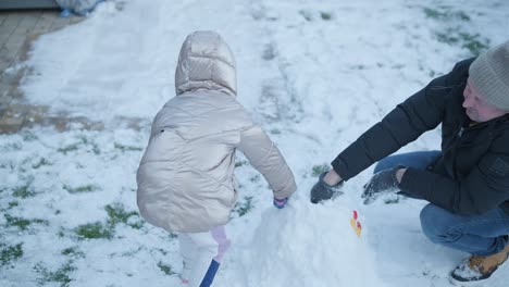 grandfather and granddaughter having fun in the snow