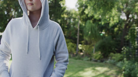 caucasian woman in white hooded top in sunny garden in slow motion with copy space