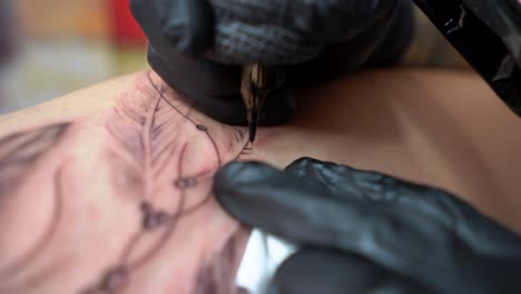 artista de cultivo dibujando tatuaje en el cuerpo del cliente en la tienda