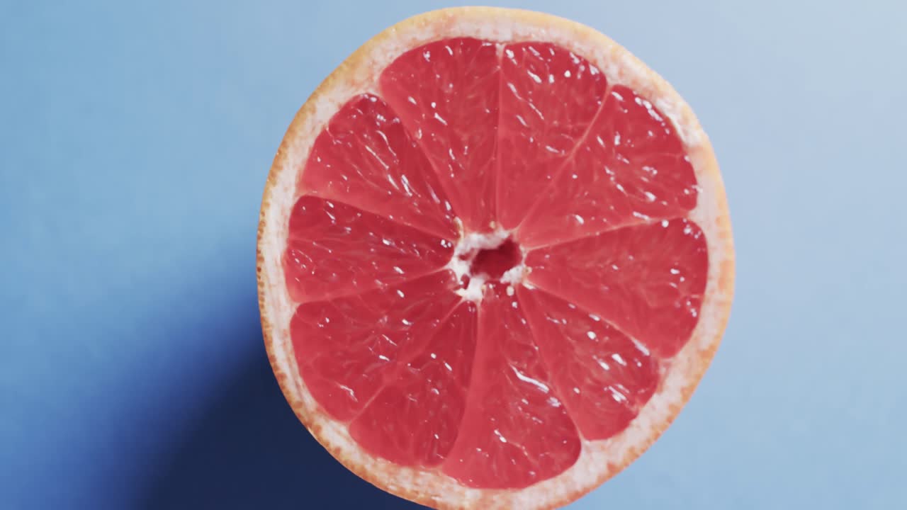 video de pomelo rojo en rodajas con espacio de copia sobre fondo azul