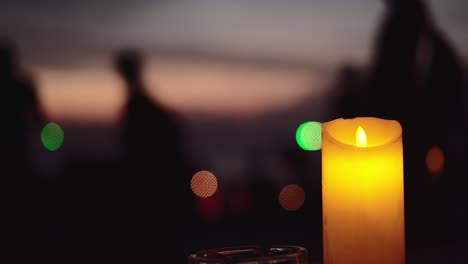 luz de velas con gente borrosa caminando en la playa durante la puesta de sol en el fondo