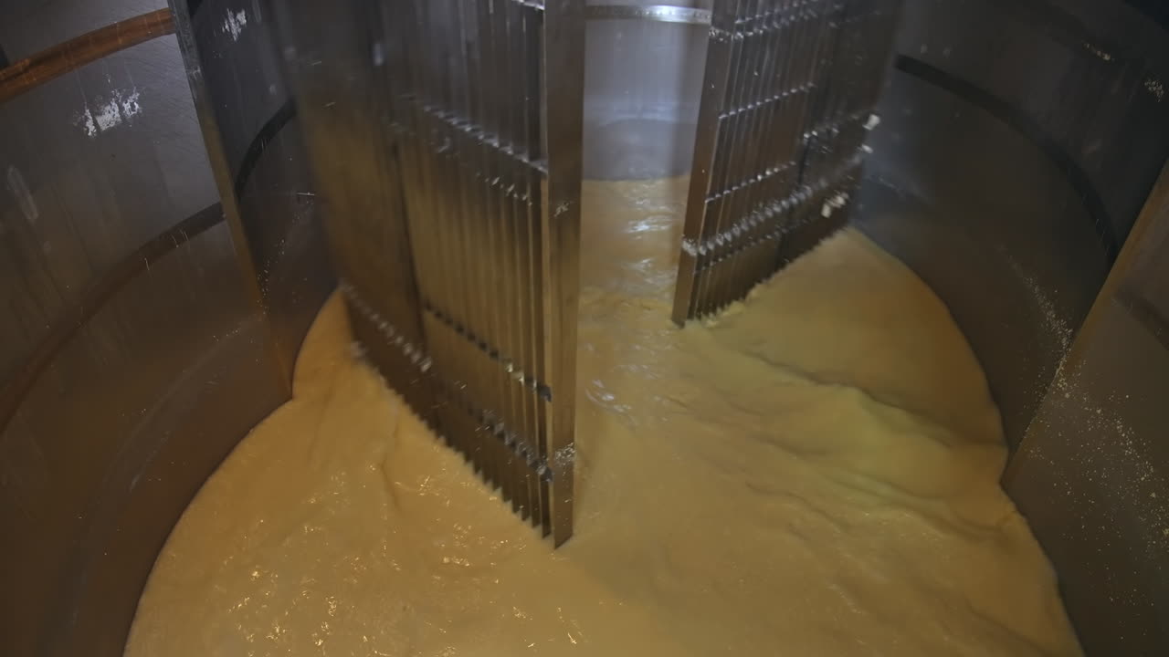 Container for butter production. Stainless reservoir with creamy liquid on a dairy plant. Metal equipment for making butter from milk products. Close-up.