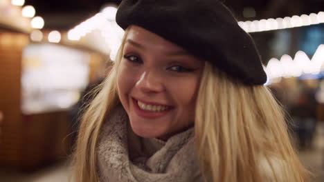 retrato de una mujer sonriente disfrutando del mercado de navidad por la noche