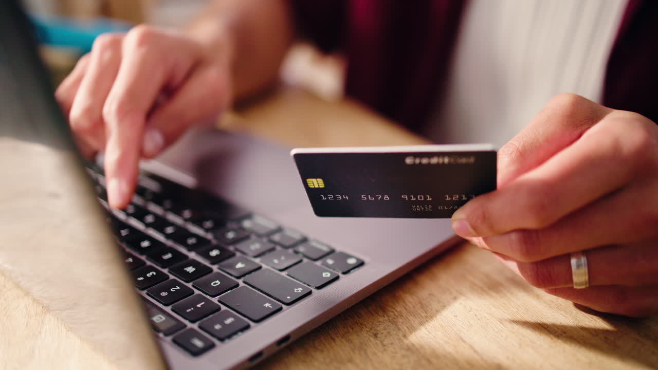 Primo piano delle mani che digitano i dettagli della carta di credito sul laptop per acquisti online