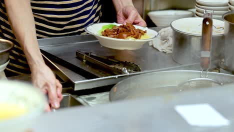 chef serves noodle soup with pork and vegetables