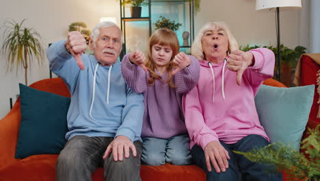 child girl kid granddaughter with grandparents showing thumbs down disapproval dissatisfied dislike