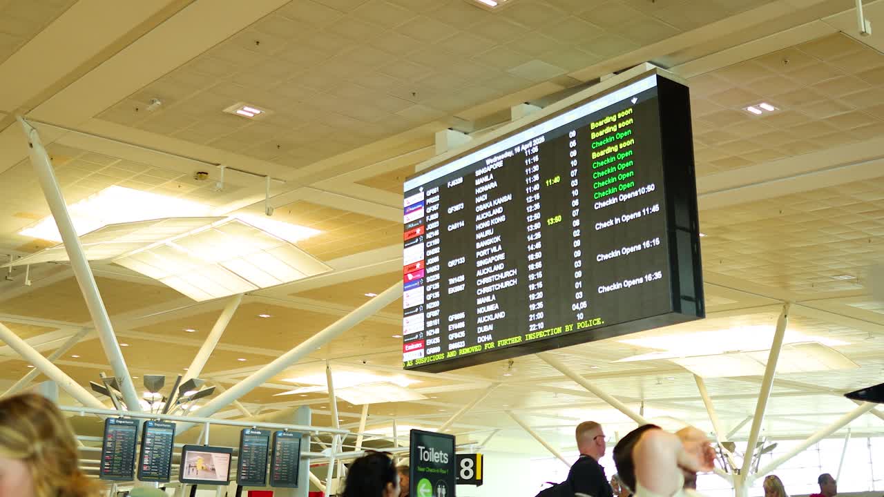 Departure board at Brisbane Airport displaying flight information. Bright lighting, bustling atmosphere, and modern architecture create a dynamic travel scene