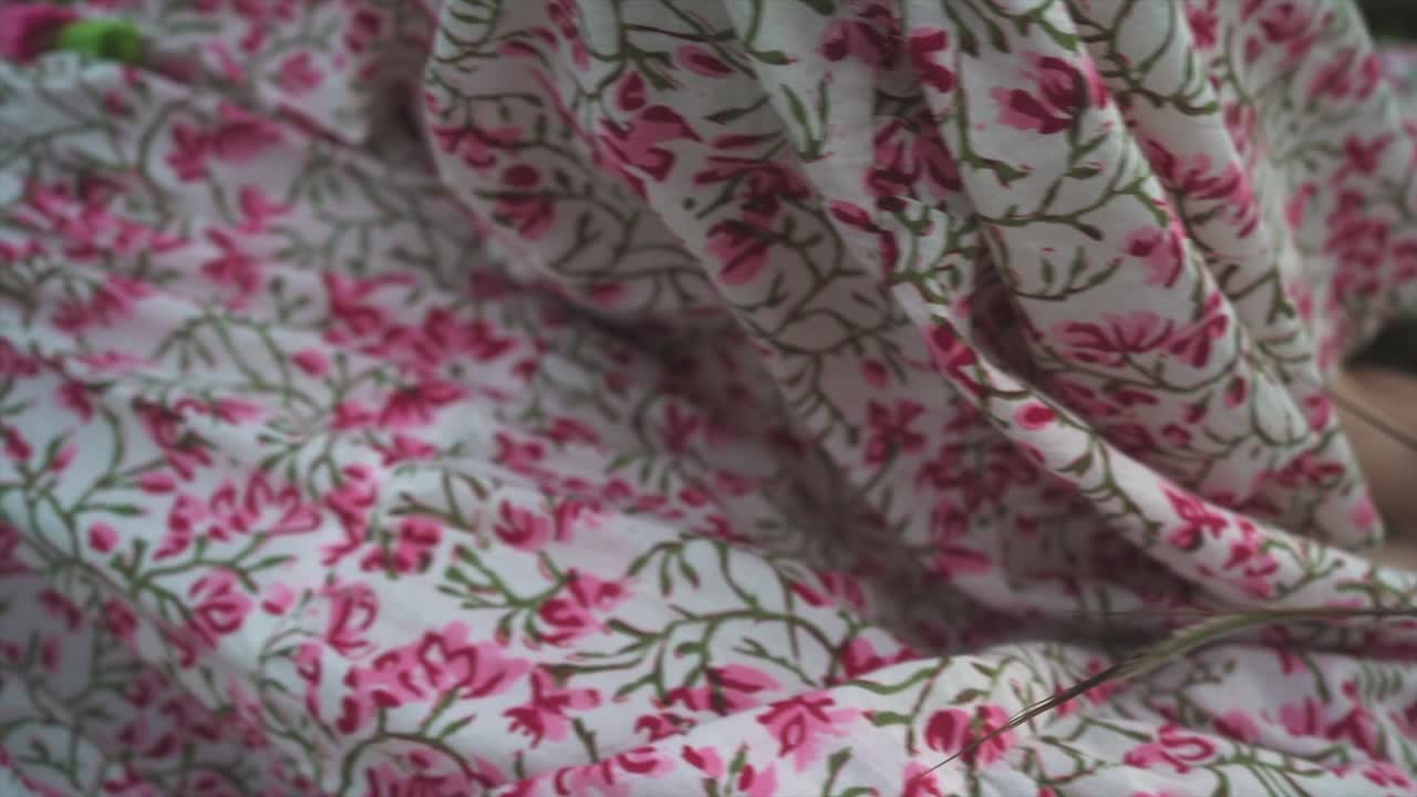 Æterisk elegance: Blomstret kjole, der sidder i græsset og danser i vinden