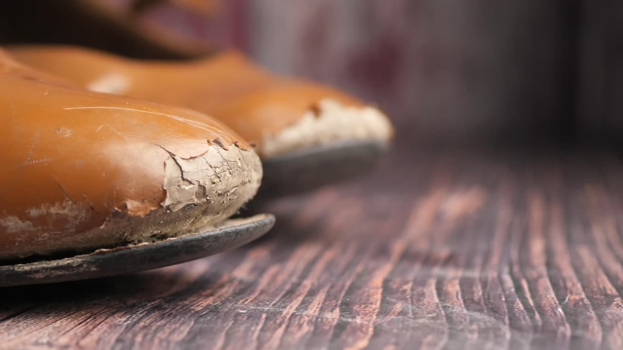 Close-up of old worn shoes on a wooden surface