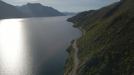 Es-Fängt-Einen-Atemberaubenden-Blick-Auf-Eine-Kurvenreiche-Straße-Ein,-Die-Parallel-Zu-Einem-Ruhigen-See-Verläuft