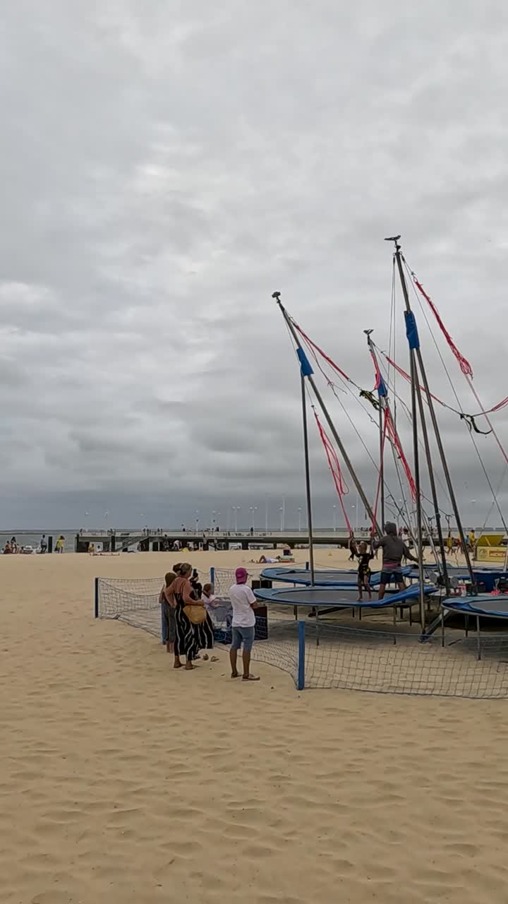 모래 해변 에서 트램폴린 을 즐기는 사람 들