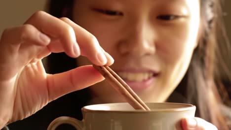 an engaging moment: a young woman enjoys a flavorful experience as she delicately dips a cinnamon stick into her beverage, highlighting cultural and culinary delights