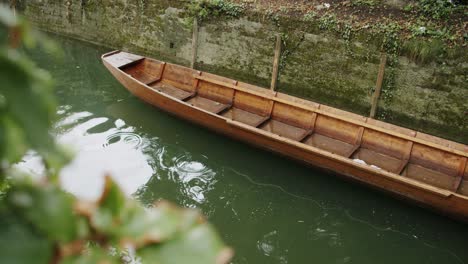 medium wide shot of a small wooden boat floating on a calm river