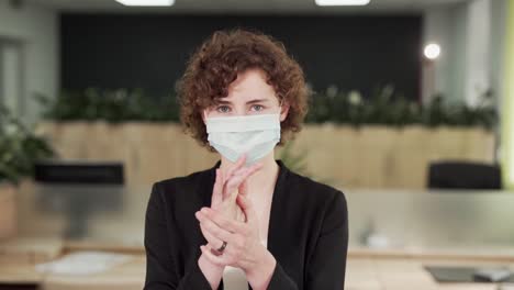 close-up-portrait-of-a-curly-girl-in-a-mask-splashing-on-the-hands-of-an-antiseptic