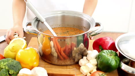 woman stirring soup and adding mushrooms