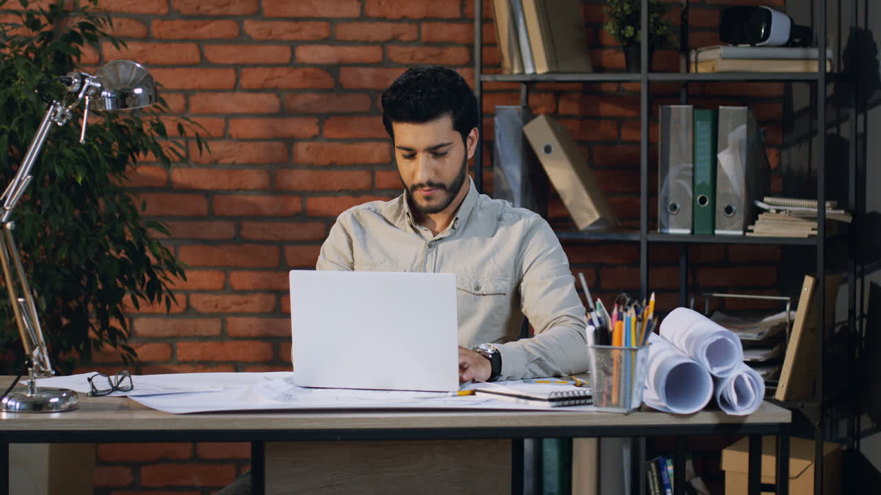 Young Arabian Architect Finishing His Project On The Laptop And Being Cheerful In His Office