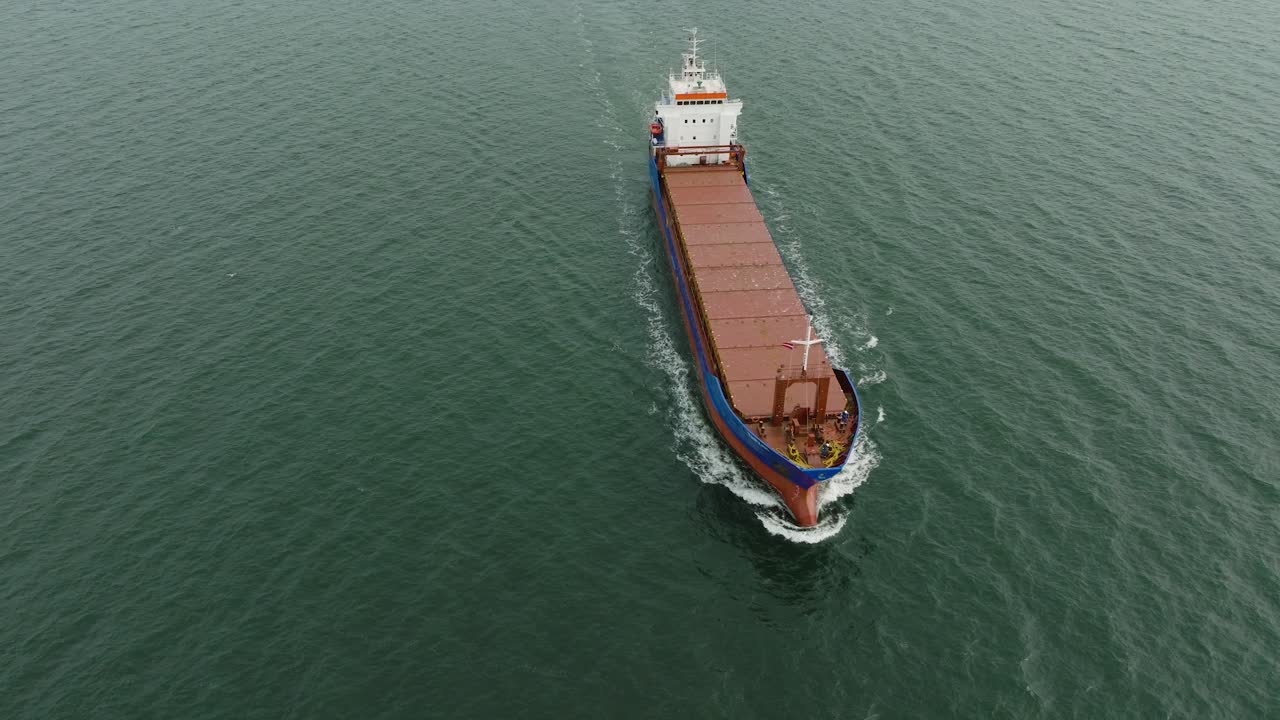 vista aérea del gran buque de carga azul que sale del puerto de liepaja, puente de karosta, día ligeramente nublado, mar báltico tranquilo, tiro de avión no tripulado de ojo de pájaro moviéndose hacia atrás