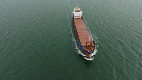 aerial establishing view of large blue cargo ship leaving port of liepaja , karosta bridge, slight overcast day, calm baltic sea, birdseye drone shot moving backward