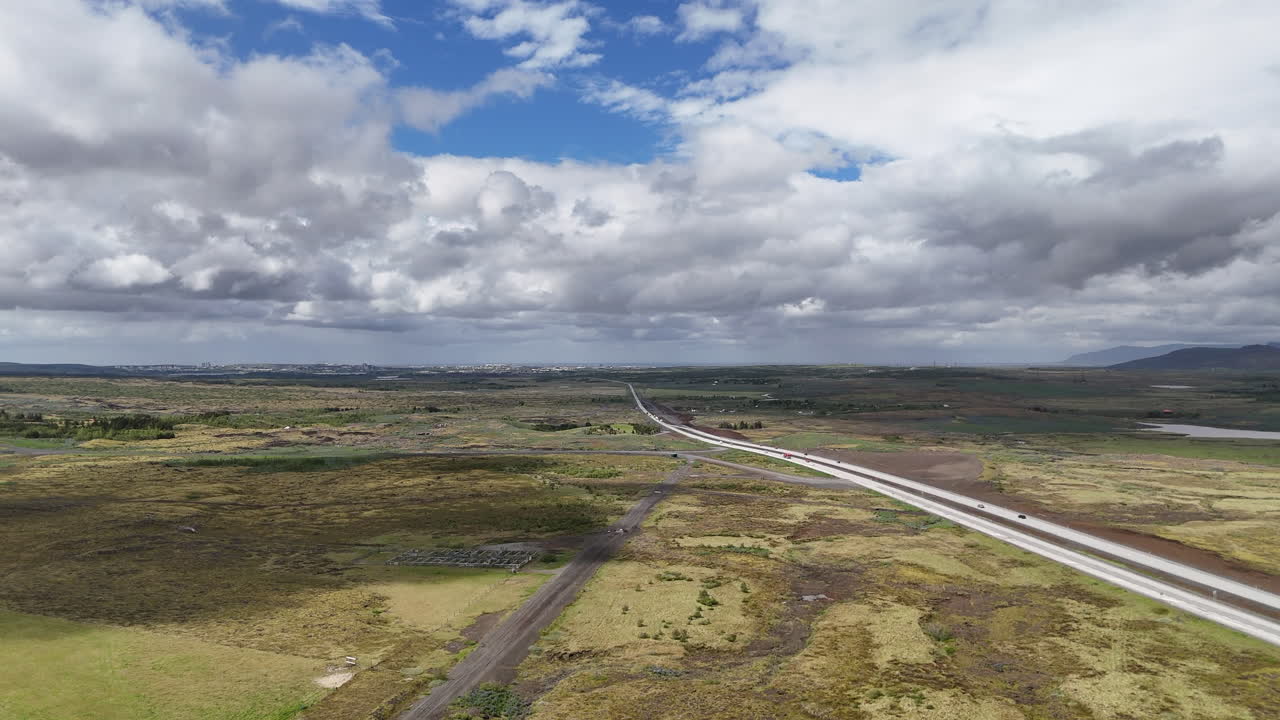 Vista aerea della Strada 1 islandese vicino a Reykjavik che attraversa vaste pianure vulcaniche sotto un cielo nuvoloso e luminoso, rivelando l'iconica strada ad anello attraverso aspri paesaggi aperti