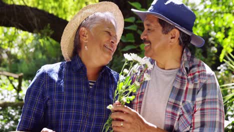 una pareja de ancianos oliendo flores.