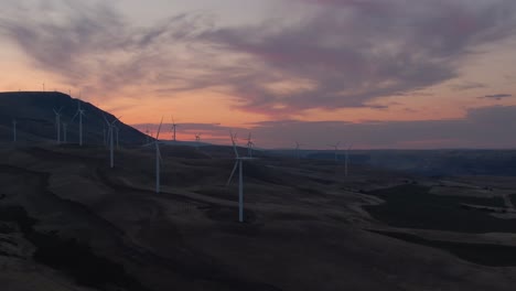 beautiful aerial landscape view of wind turbines on a windy hill during a colorful sunrise