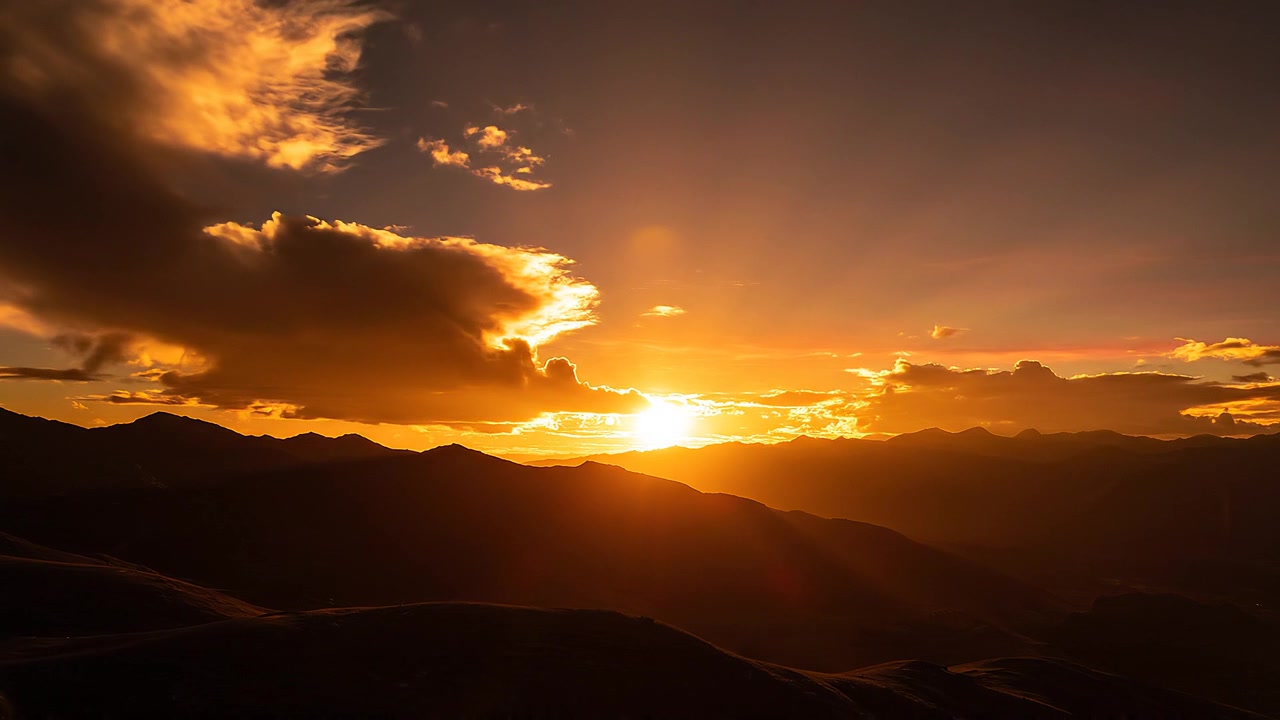 Pôr do sol cênico na montanha com raios de sol dourados dramáticos sobre o horizonte.