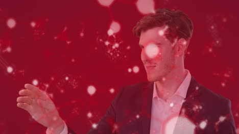 animación de un hombre caucásico vestido con un traje tocando modelos de moléculas flotando sobre un fondo rojo