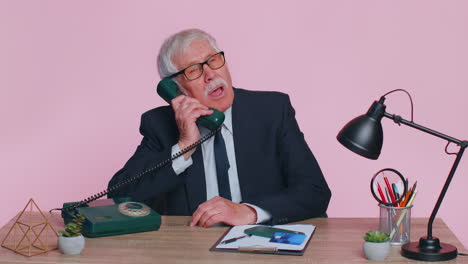 Crazy-senior-businessman-talking-on-wired-vintage-telephone,-fooling,-making-silly-humor-comic-faces