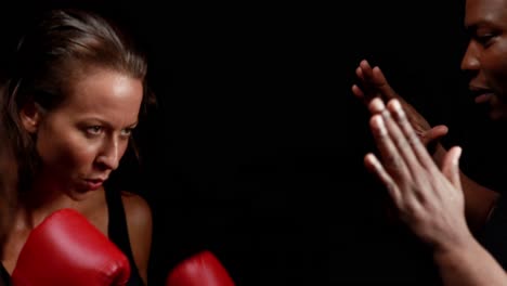 una boxeadora golpeando la mano del entrenador