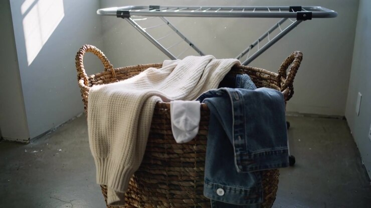 Shifting window sunlight brightening wicker basket at laundry corner, with sweater sock denim rack