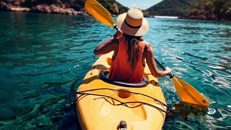 Aerial video shot of a woman kayaking on clear turquoise waters, showcasing a vibrant summer