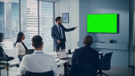 office conference room meeting presentation: motivated caucasian businessman talks, uses green screen chroma key wall tv. successfully presenting a product to group of multi-ethnic investors