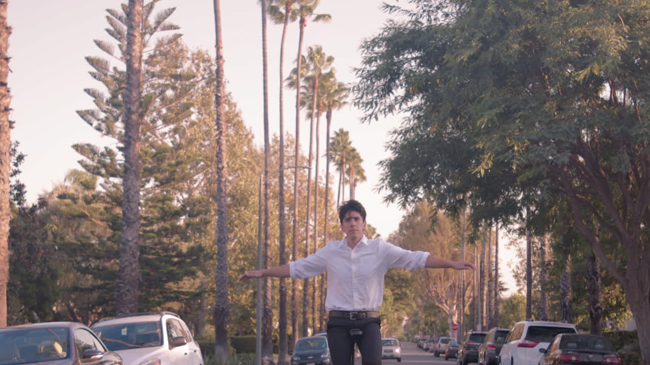 Man balancing on a unicycle in a street with palm trees