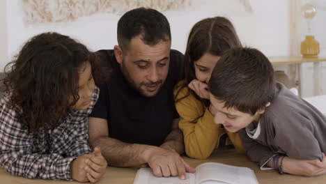 caucasian father checking homework with children.