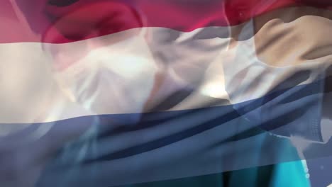 Animation-of-netherlands-flag-over-diverse-male-and-female-surgeon-performing-operation-at-hospital